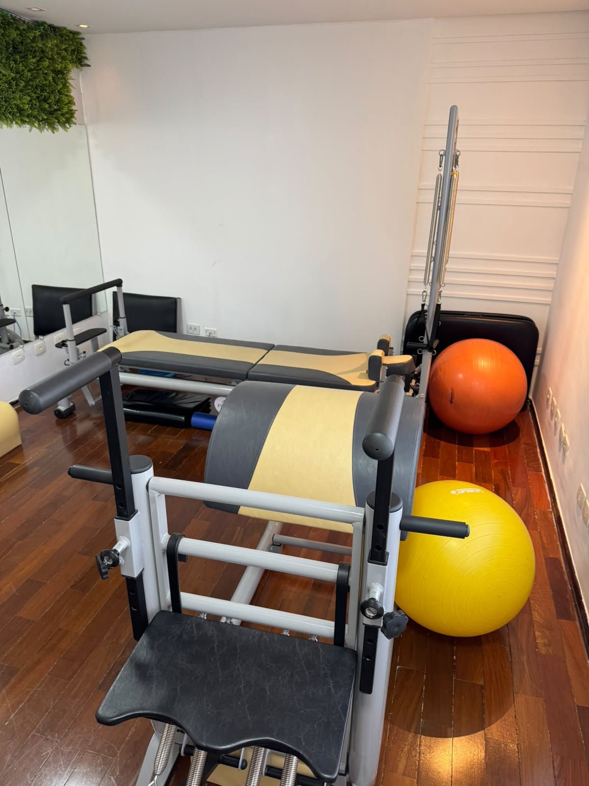 Estúdio de Pilates com reformers, bolas e espelho.